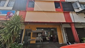 A multi-story building with a ground-level shop entrance, a visible staircase, and a large potted plant in the foreground. - OYO 90086 My Seven Days Inn (Masai)