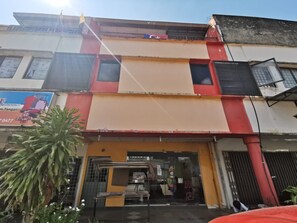 A multi-story building with a ground-level shop entrance, a visible staircase, and a large potted plant in the foreground. - OYO 90086 My Seven Days Inn (Masai)