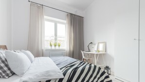 A bedroom with a bed, a desk, and a window with curtains. - P&O Andersa (Warsaw)