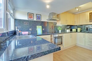 Privékeuken | Een koelkast met diepvriezer, een microgolfoven, een oven, een kookplaat