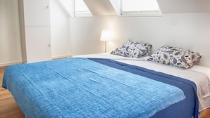 A bedroom with a bed, a nightstand, a lamp, and a wardrobe.