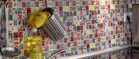 A kitchen with a colorful tile backsplash and a stainless steel sink.