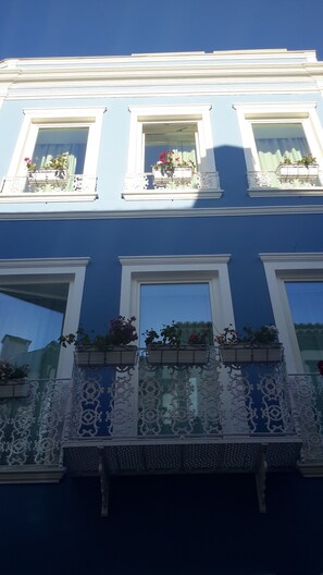 Un bâtiment doté de trois fenêtres, chacune ayant un balcon. Les balcons sont ornés de balustrades blanches décoratives et agrémentés de jardinières.