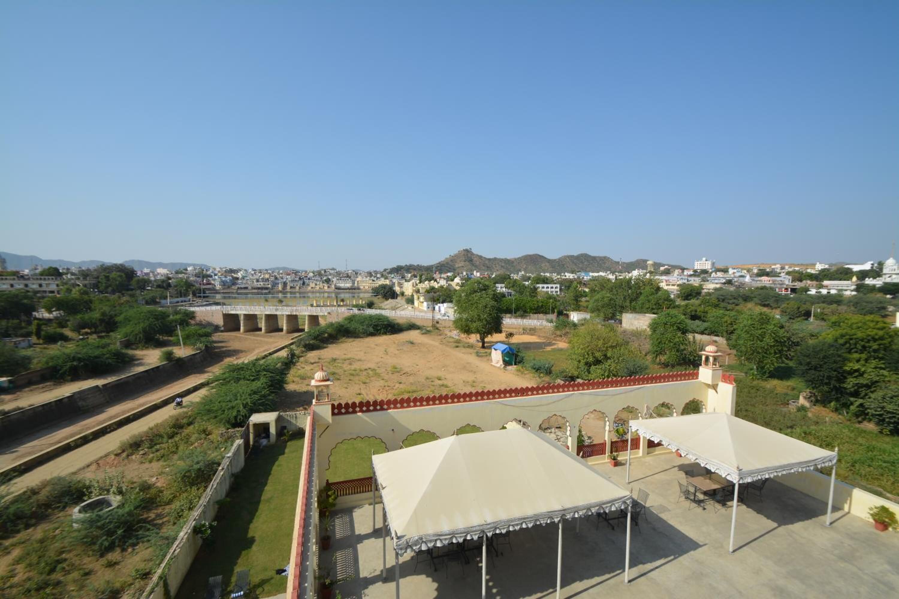 A rooftop terrace with a view of a bridge and distant buildings, surrounded by greenery.