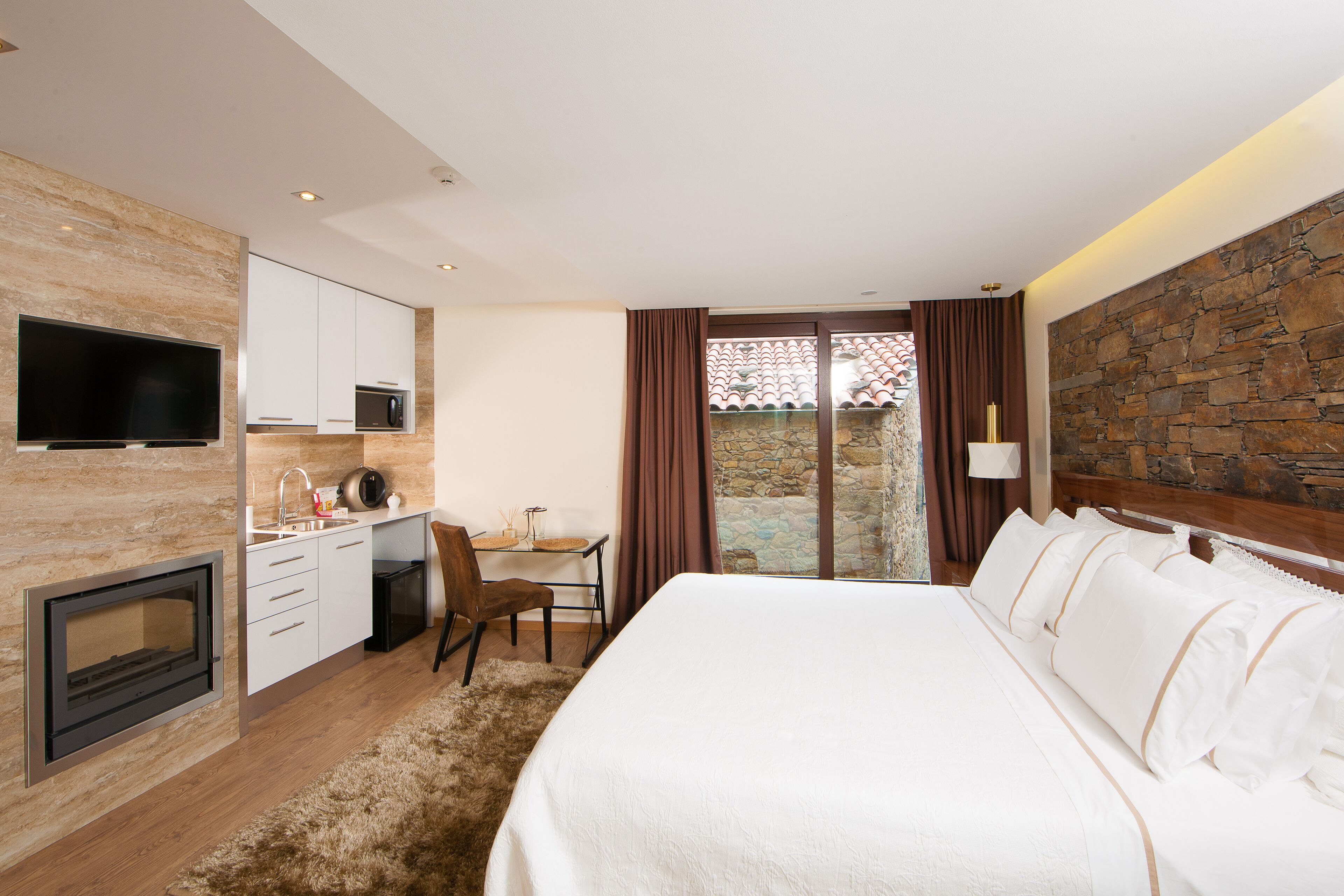 Una habitación de hotel moderna con cama, escritorio, televisor y chimenea.