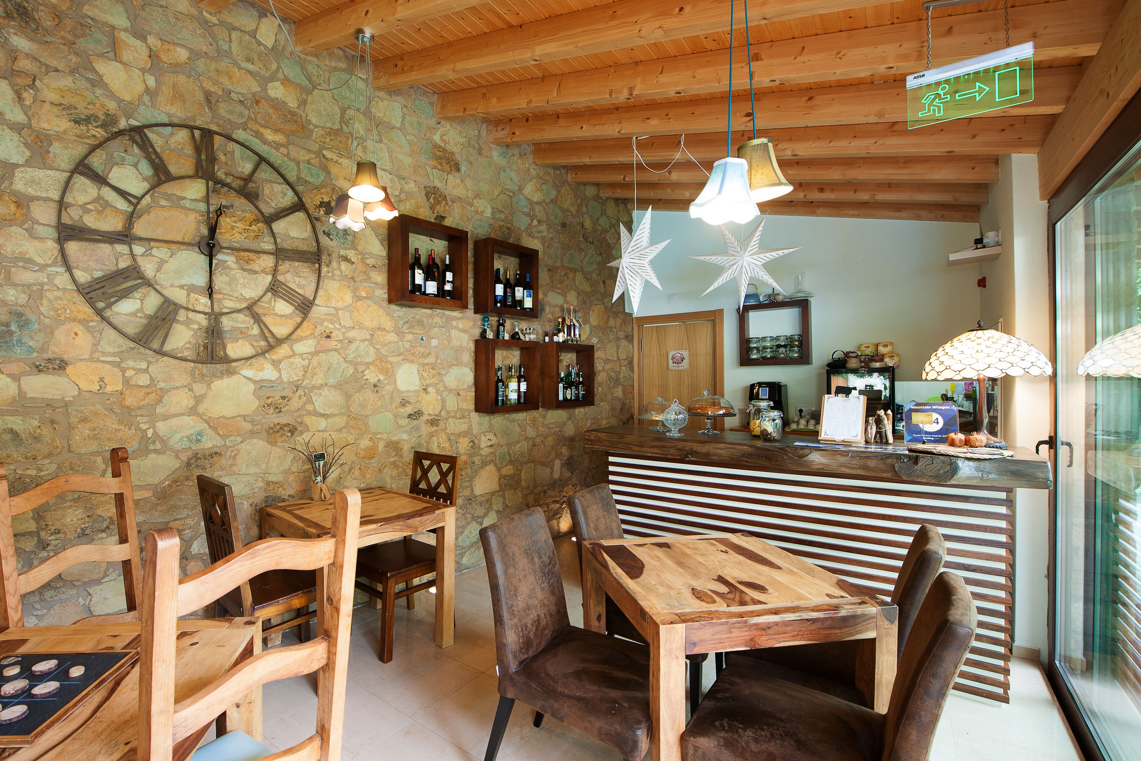 Interior rústico com parede de pedra, móveis de madeira, um relógio grande e um espaço bar.