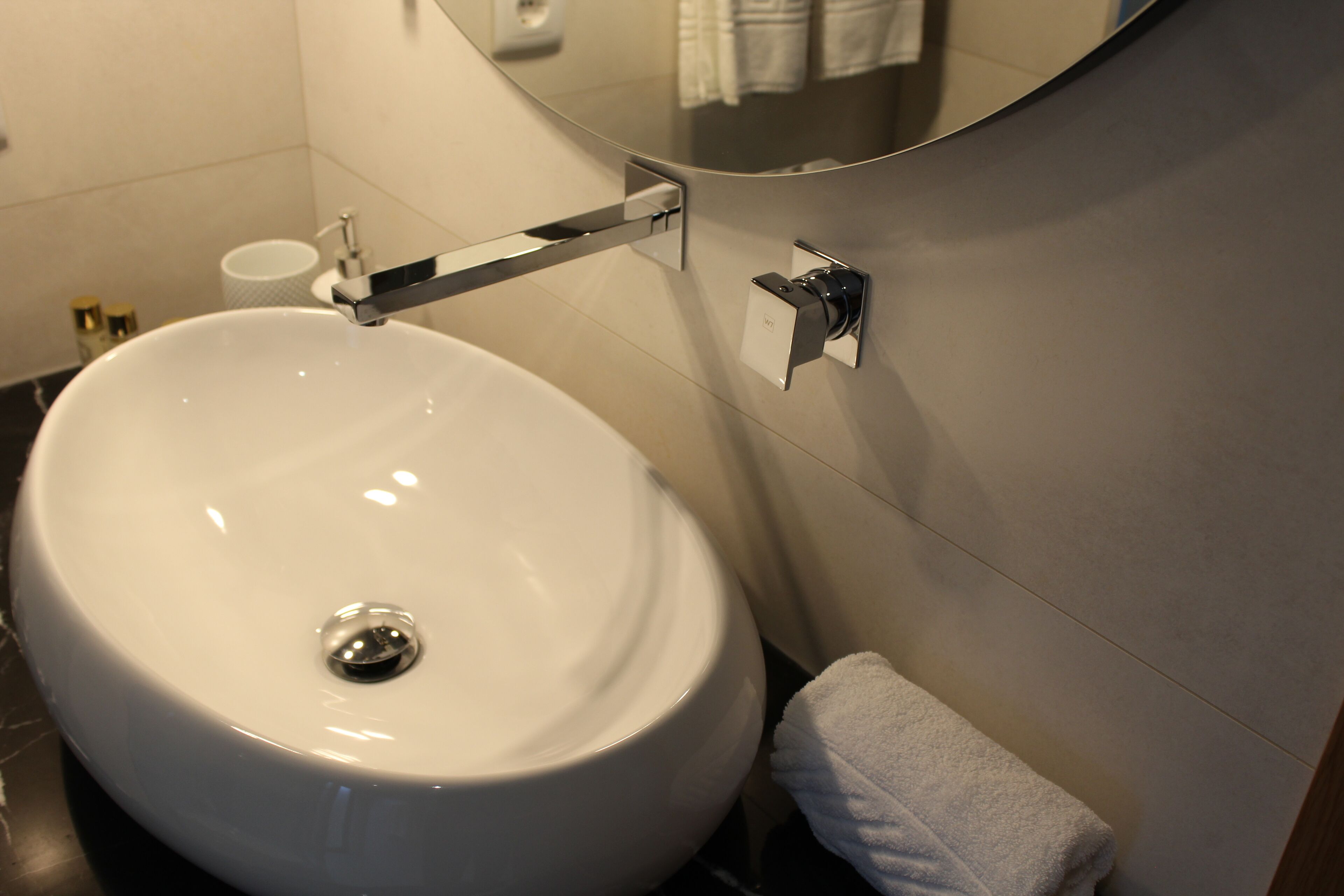 A modern bathroom with a white sink, a towel rack, and a mirror.