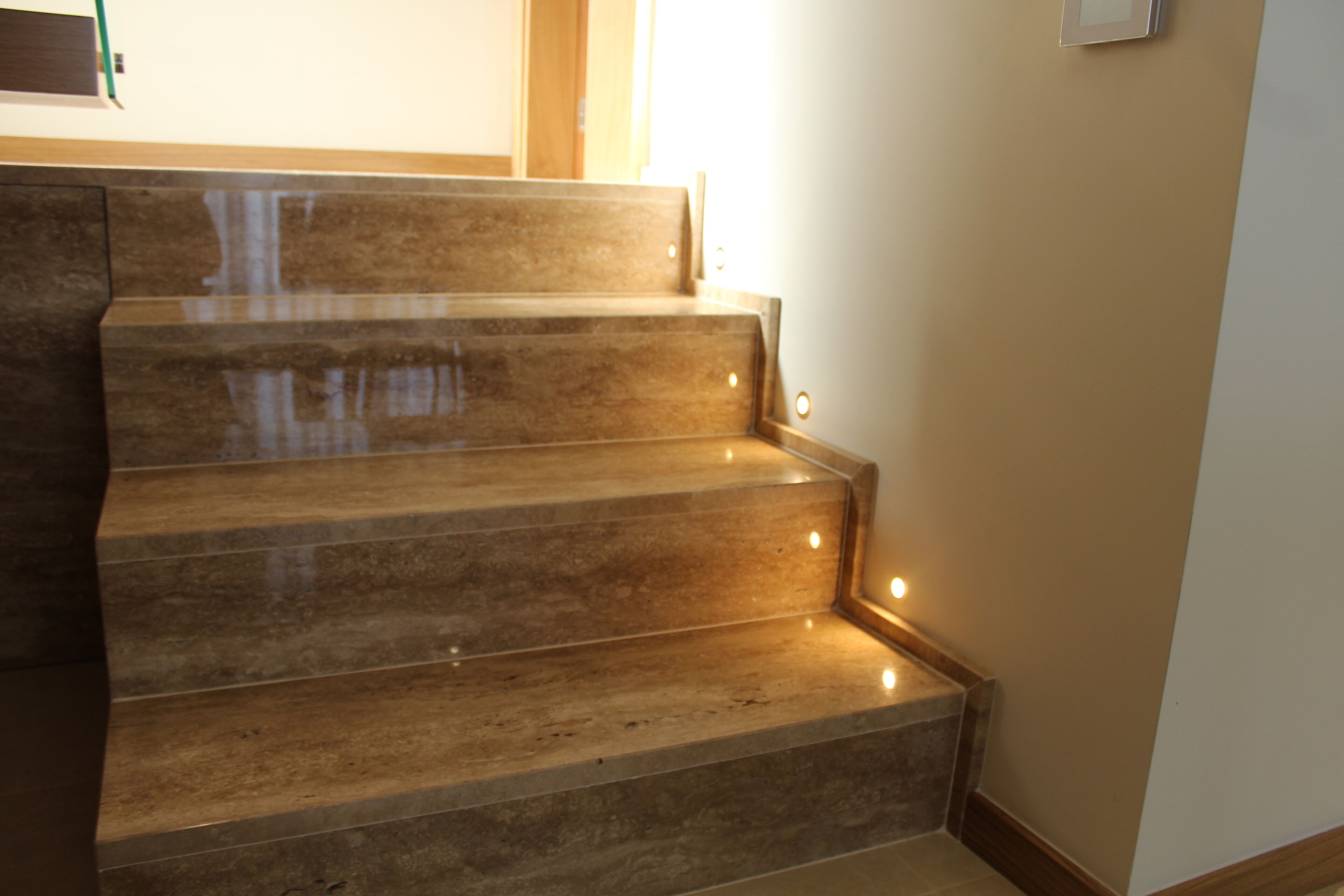 A set of marble stairs with built-in lighting, leading to a landing.
