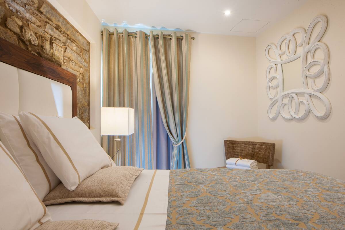 A hotel room with a bed, curtains, a wall-mounted artwork, and a headboard.