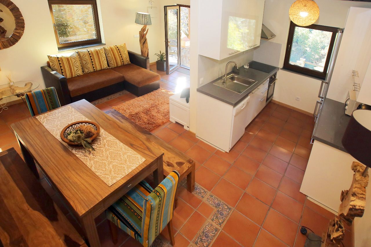 A compact living space with a dining area, kitchenette, and a sofa with patterned cushions.