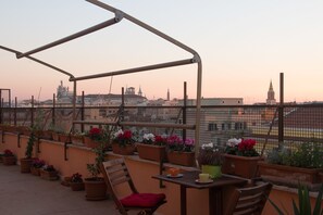 Una terraza en la azotea con una pérgola de madera, plantas en macetas y una mesa con sillas.