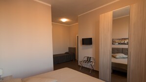 A hotel room with a bed, a chair, a television, and a wardrobe with a mirror.