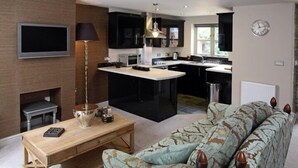 Una cocina moderna con una isla central, un comedor con una mesa de madera y un sofá estampado.