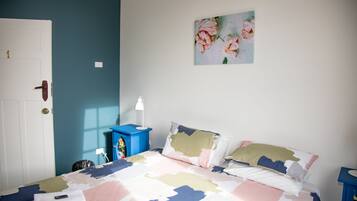 Et soveværelse med en seng, et natbord, en lampe, en dør og et billed på væggen.