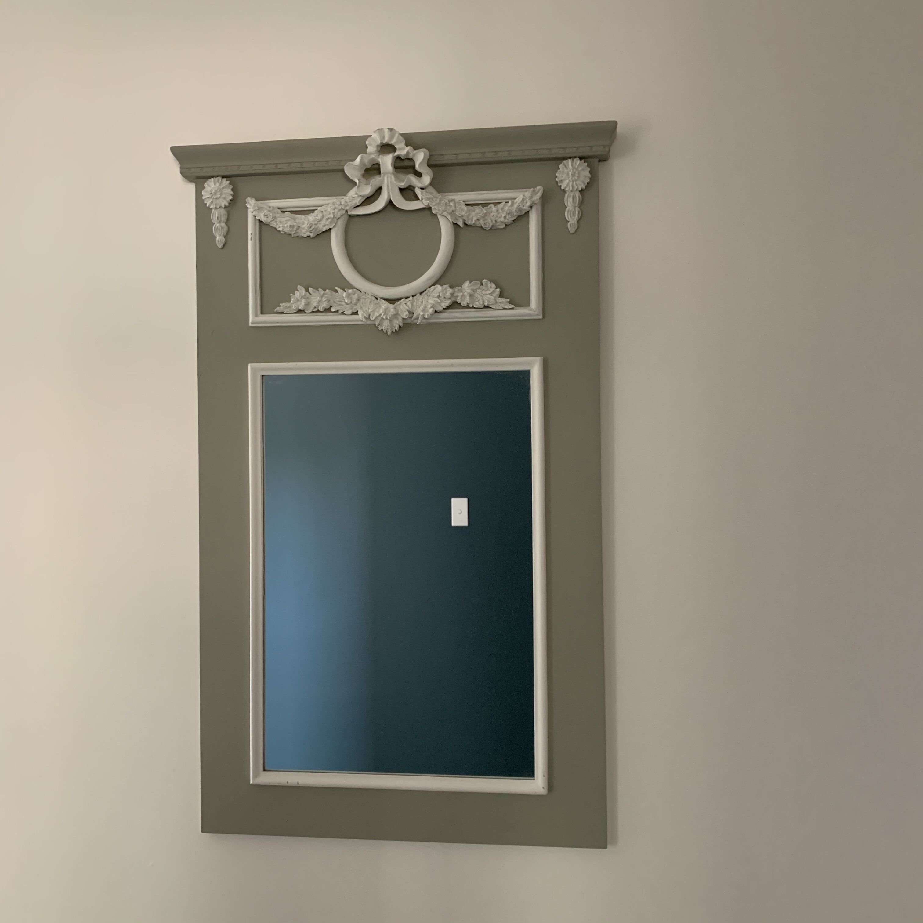 Un miroir encadré avec un décor ornemental sur le dessus.