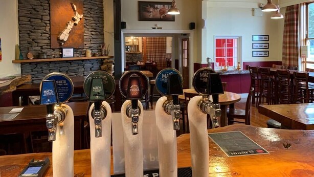 A bar area with multiple taps, a stone wall, and a view of the restaurant in the background. - The Brown Pub (Methven)