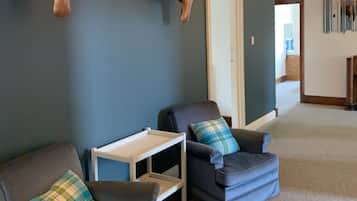 Una sala de estar moderna con dos sillones de cuero, una pequeña mesita blanca y una lámpara colgante roja.