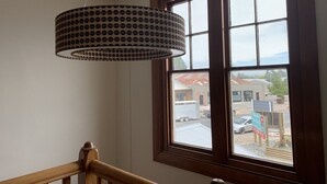 A room with a large window, a wooden railing, and a patterned hanging light fixture. - The Brown Pub (Methven)
