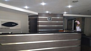 Una recepción con un reloj encima, un florero y un diseño moderno con líneas horizontales.