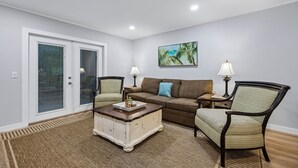 A living room with a sofa, two chairs, a coffee table, and a painting on the wall. - Amelia Landings Condo, Easy Access to the Pool and Short Walk to the Beach by RedAwning (Fernandina Beach)