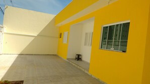 A yellow building with a tiled floor and a window with blinds. - Pousada Recanto do Luar (Taubate)