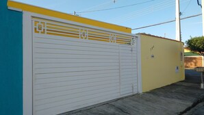 A building with a closed white garage door, a yellow wall, and a blue wall. - Pousada Recanto do Luar (Taubate)