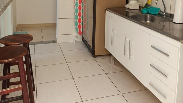 A compact kitchen with white cabinets, a refrigerator, a coffee maker, and a small sink. - Pousada Recanto do Luar (Taubate)