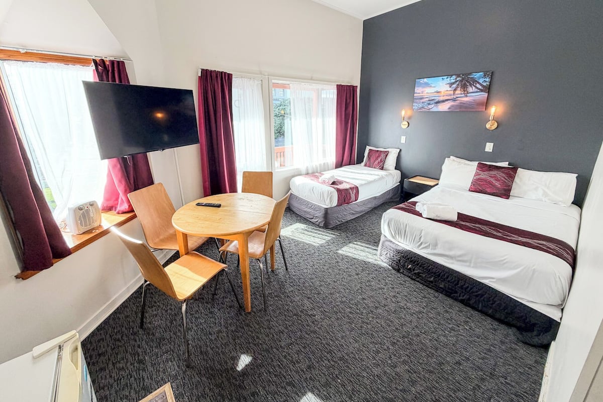 Une chambre d’hôtel avec un lit, un bureau, une chaise, une télévision et un tableau au mur.