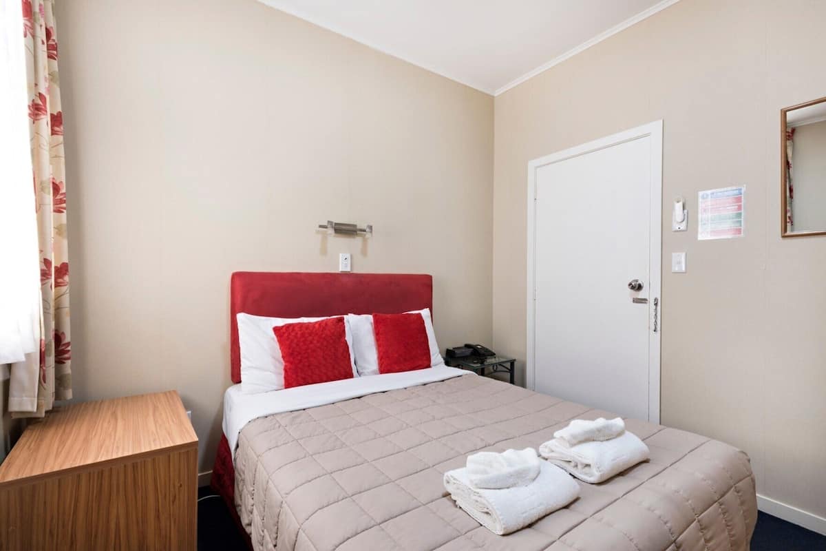 Une chambre d’hôtel avec un lit, une table de chevet, une porte et un miroir.