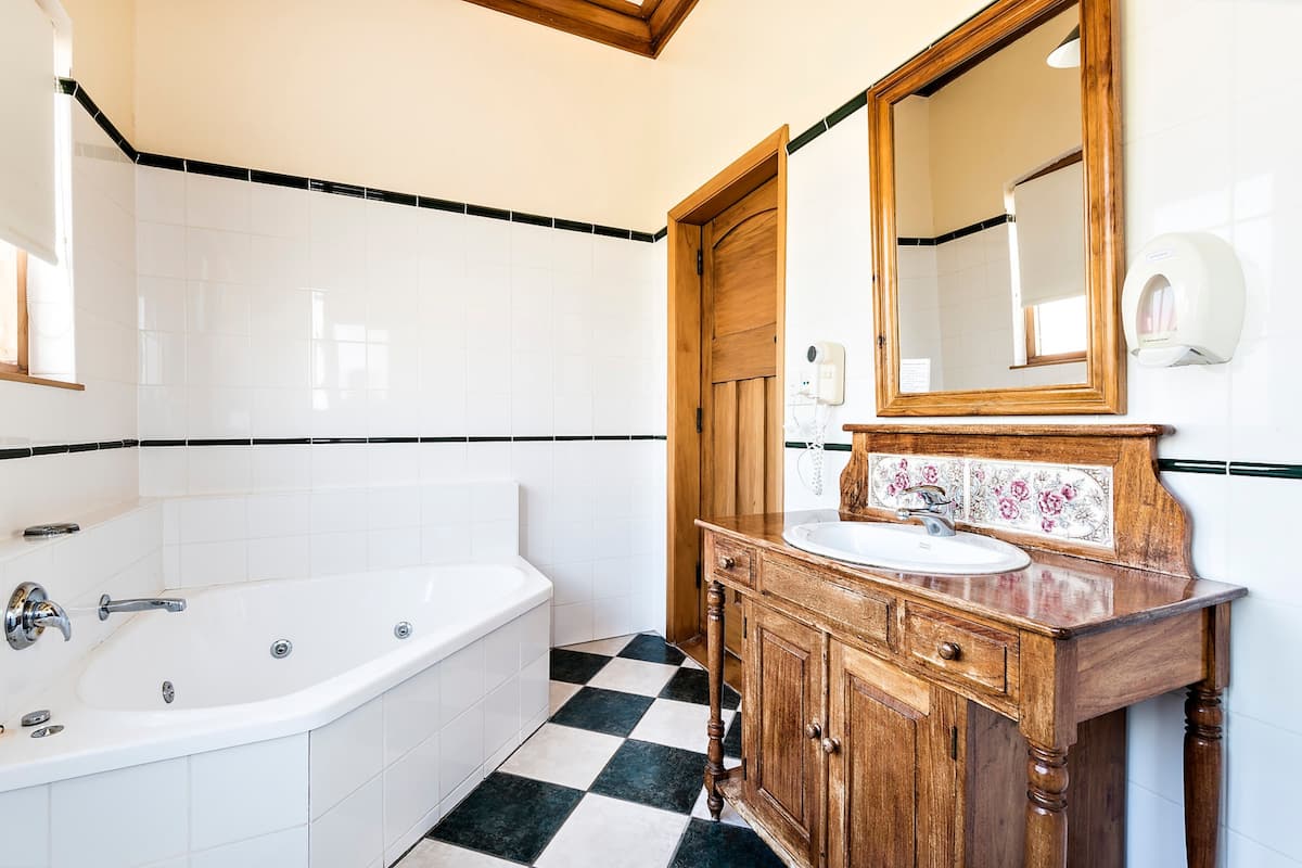 Une salle de bain avec une baignoire blanche, un meuble-lavabo en bois et un grand miroir.