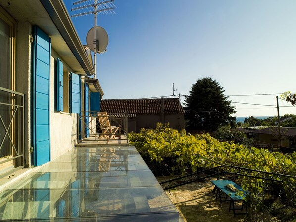 A modern house with a glass balcony, a satellite dish, and a view of the sea.