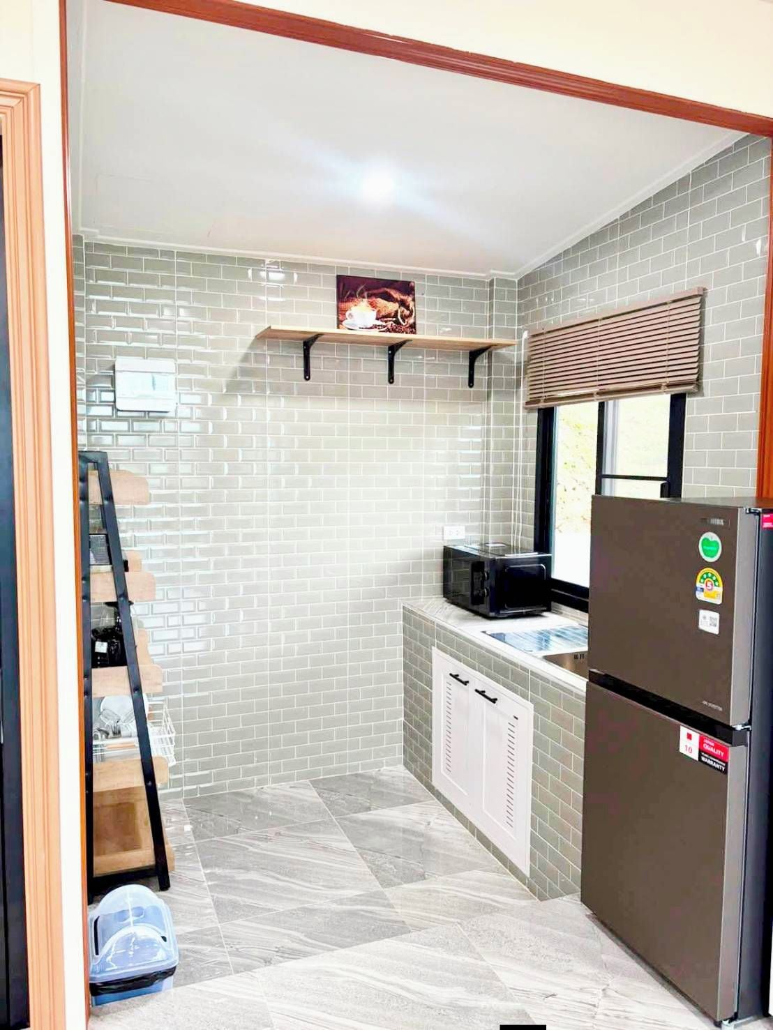Cocina compacta con refrigerador, microondas y ventana con persianas.