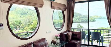 A living room with a leather sofa, a glass coffee table, and a flat-screen TV mounted on the wall.