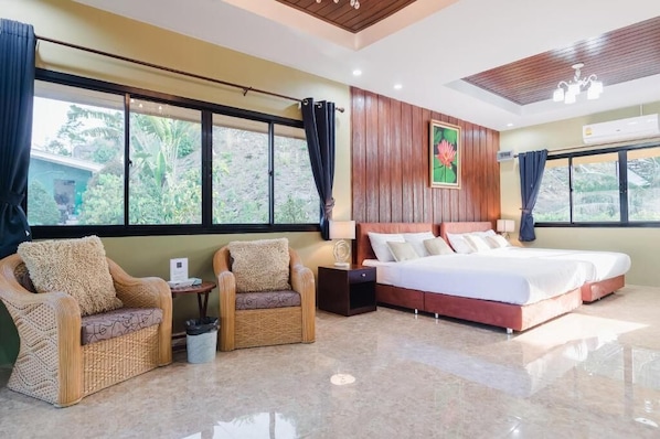 A hotel room with a bed, two chairs, a nightstand, a window with curtains, and a painting on the wall. - Siray Green Resort (Ratsada)