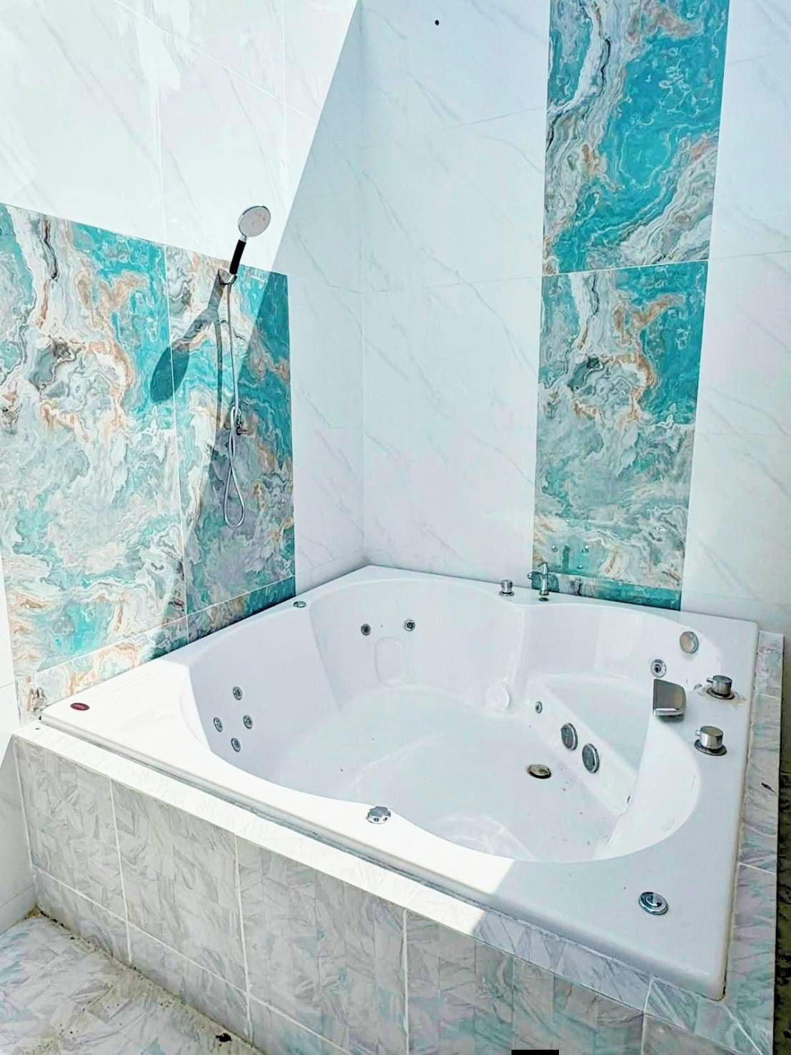 A bathroom with a freestanding bathtub, marble-patterned walls, and a shower area.