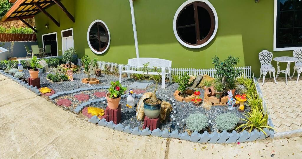 A garden with potted plants, a white bench, and a white fence.
