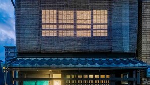 Una casa tradicional japonesa con tejado de baldosas, un portón de madera y un amplio ventanal.