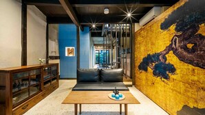 Un interior moderno con una mesa de madera, sofá de cuero negro y un cuadro abstracto grande.