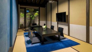 Una habitación tradicional japonesa con suelo de tatami, una mesa baja y un televisor montado en la pared.