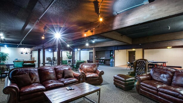 A spacious lounge area with leather sofas, a wooden coffee table, and a high ceiling with exposed beams. - Snowline Lodge Condo #9 (Deming)