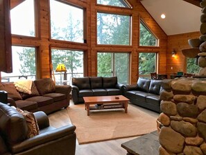 A spacious living room with large windows, a stone fireplace, and a cozy seating area.