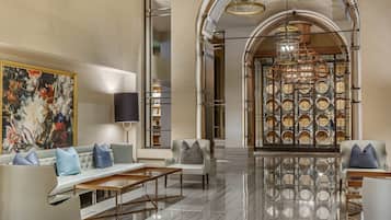 A spacious lobby with a high ceiling, a large painting on the wall, and a seating area with a sofa and armchairs.
