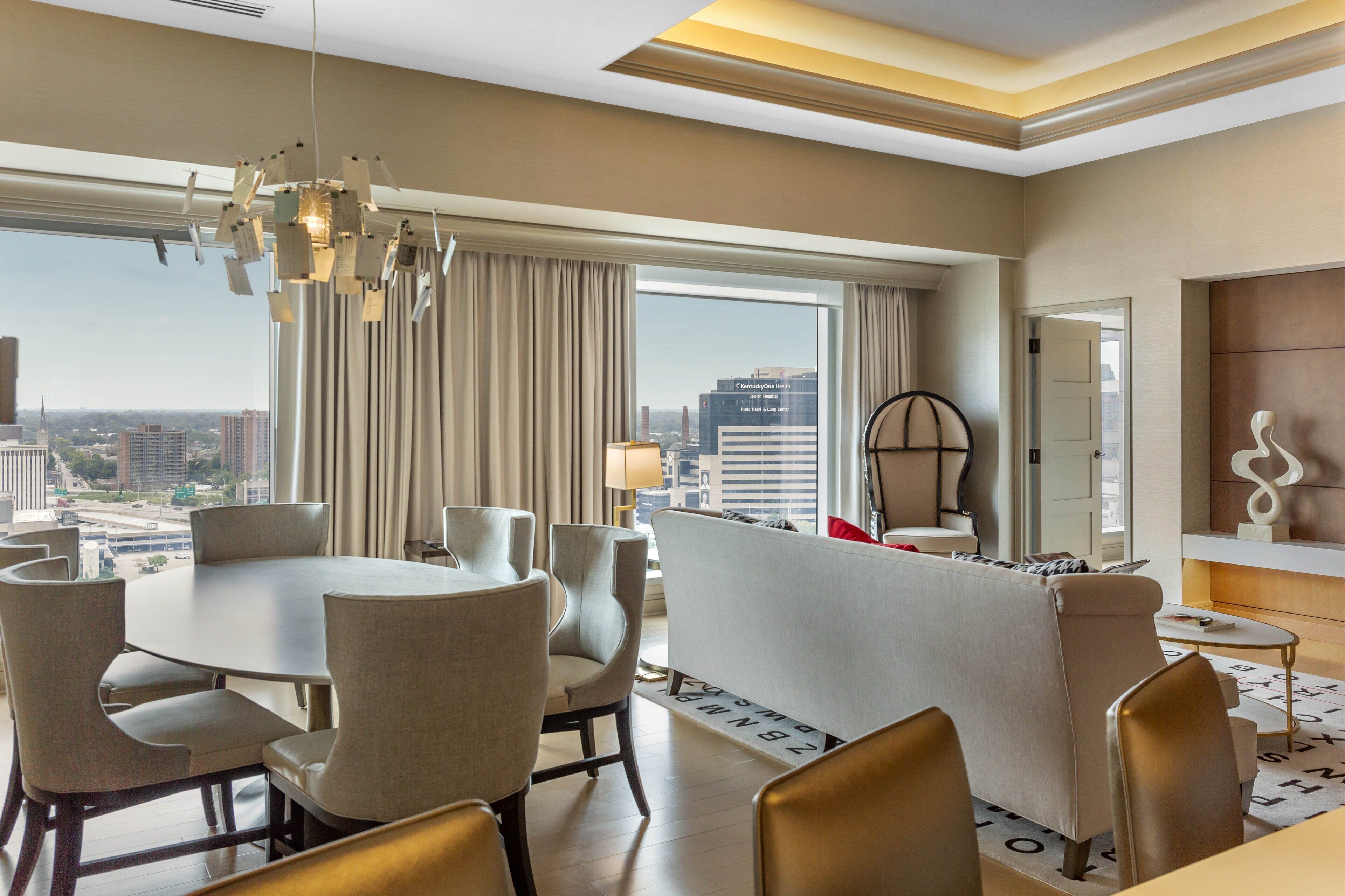 Habitación de hotel moderna con comedor, sofá y vistas a la ciudad.