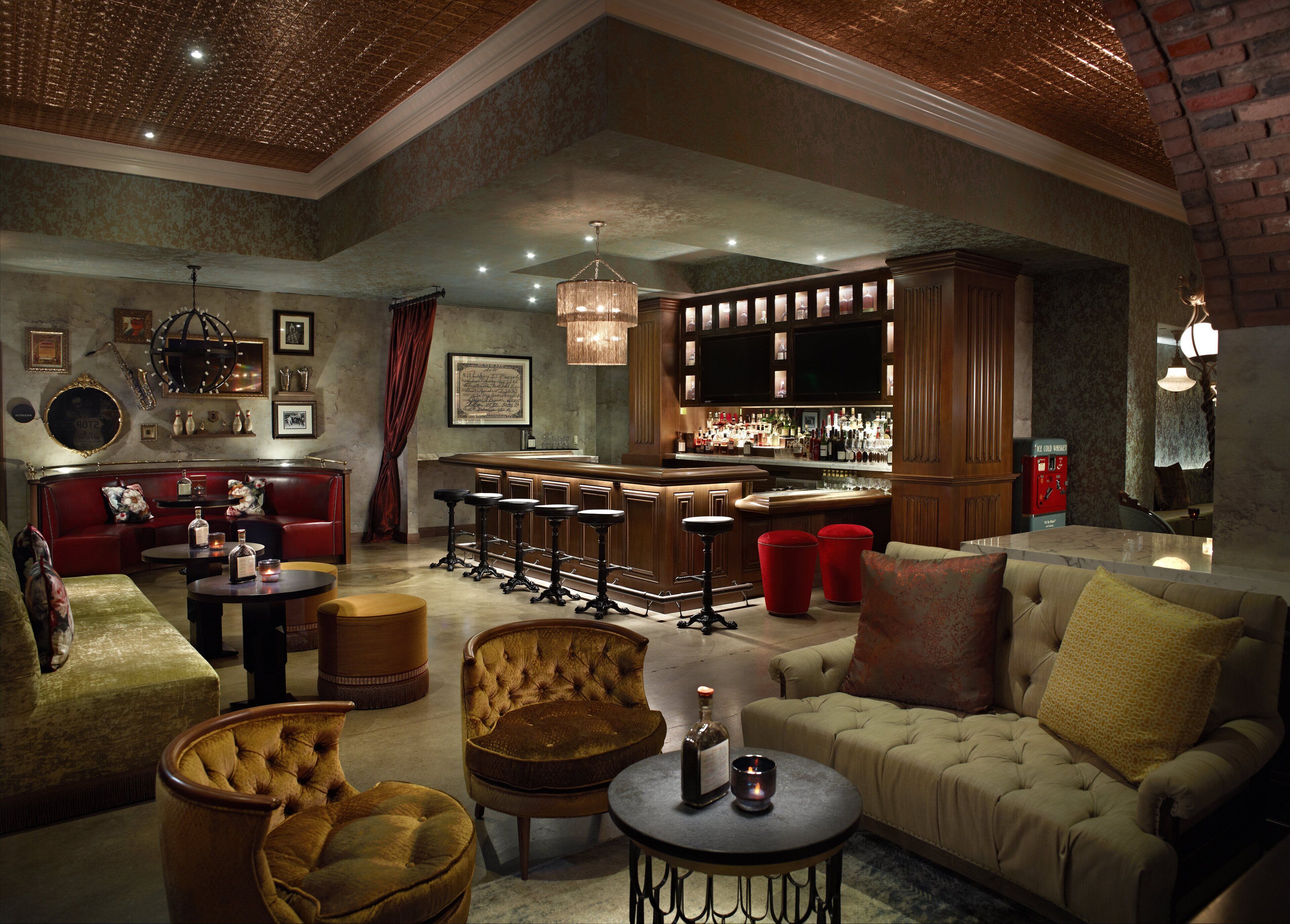 A spacious lounge with a bar area, leather seating, and a chandelier.