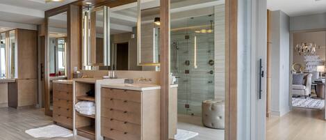 Un baño moderno con un espejo grande, dos lavamanos, una ducha a ras de suelo y una zona de estar.