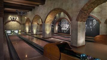 A bowling alley with multiple lanes, wooden bowling pins, and a mural on the wall.