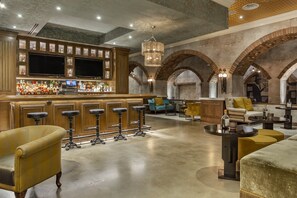 A bar area with wooden cabinets, multiple stools, and a television screen.