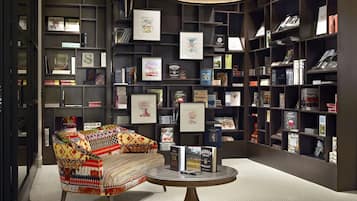 A library with bookshelves, a patterned armchair, and a table with books.