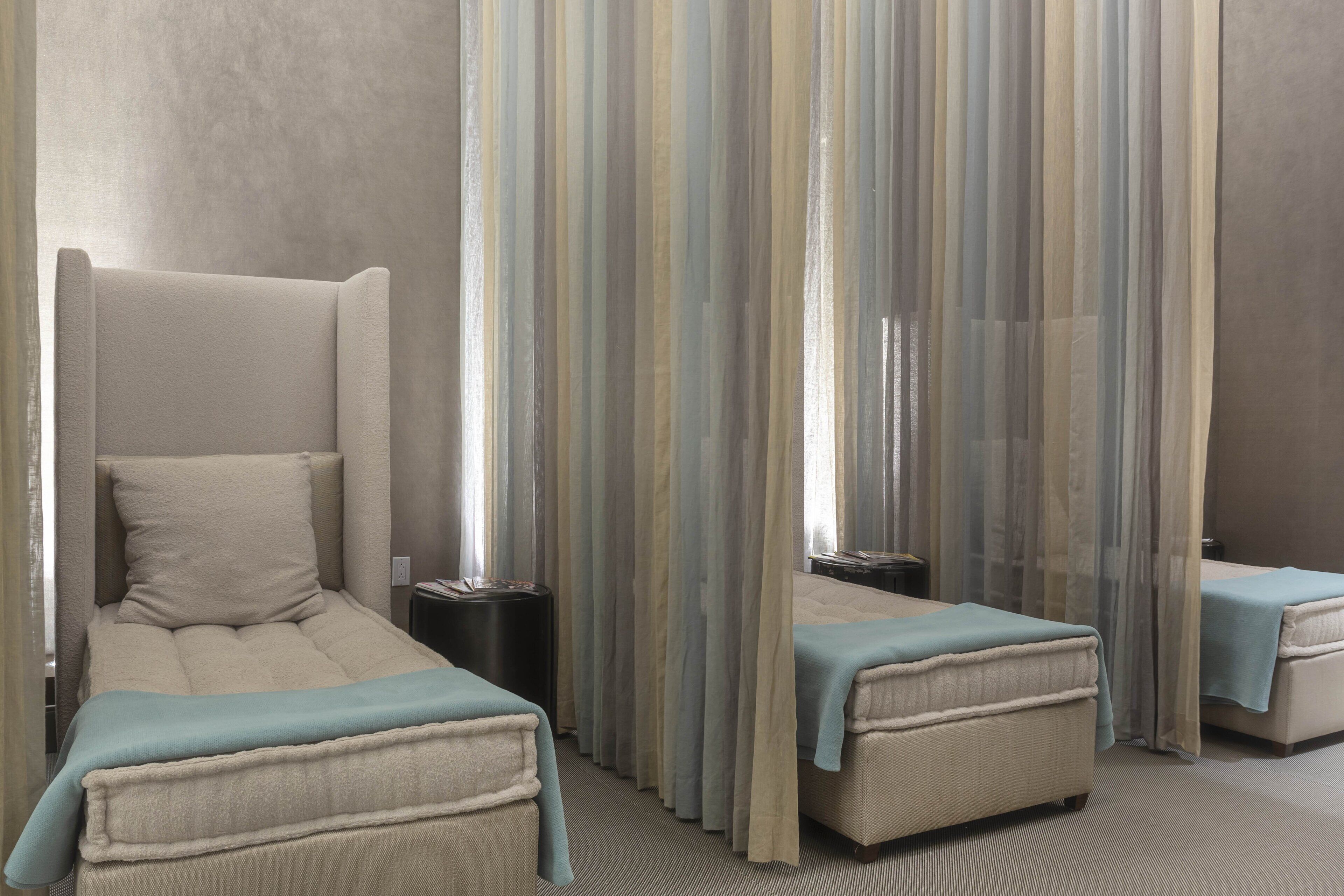 Una habitación de hotel con una cama grande, dos camas más pequeñas, una mesita de noche y un espejo.