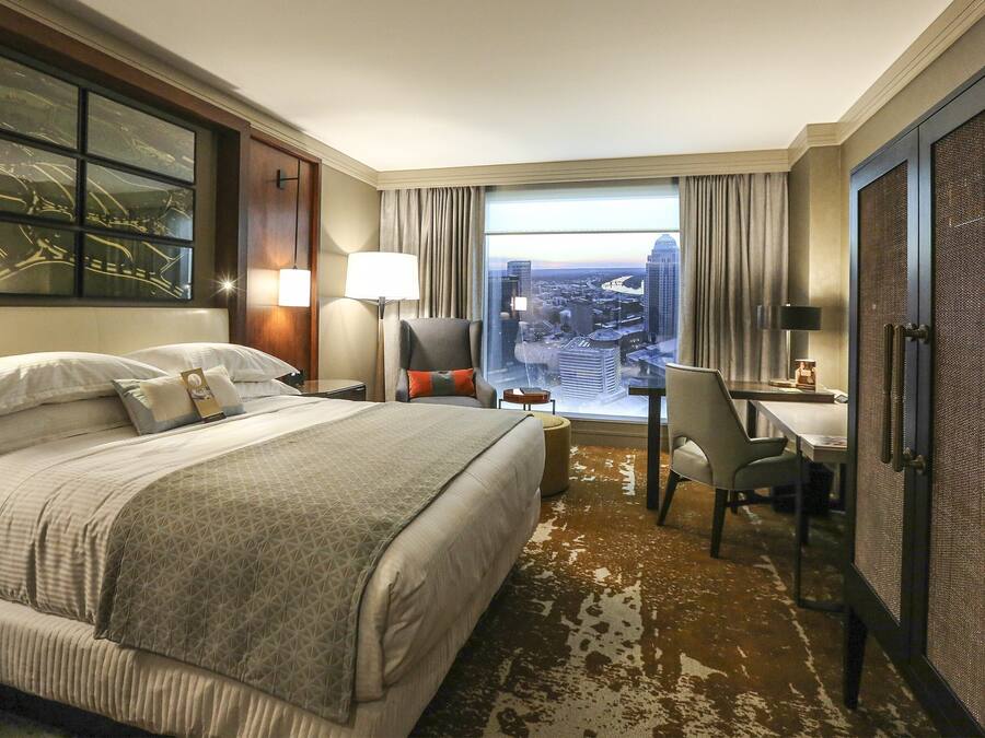 Habitació d'hotel amb un llit gran, una taula de treball i vista a la ciutat per la finestra.